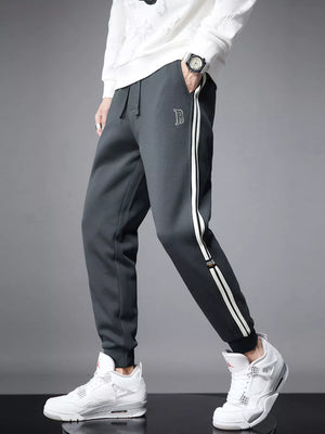 Men's dark gray cuffed joggers with white side stripes and embroidered logo.