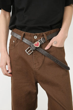 Brown wide-leg jeans with angled seams and a dark belt with a red heart charm.