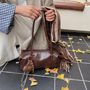 Brown pu leather shoulder bag with charm detail and scarf styling.