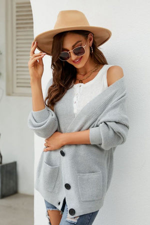 Light gray textured knit cardigan with oversized pockets and black buttons.
