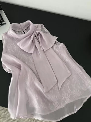 Sleeveless purple shirt with lace overlay and large satin bow detail.