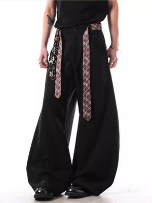 Black wide-leg sweatpants with plaid strap detail and chain accessory.