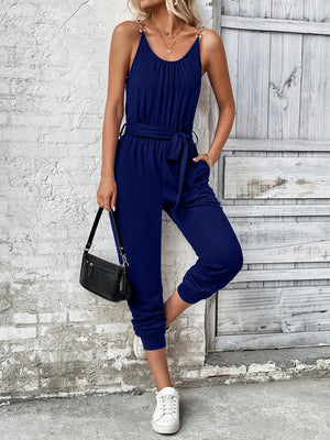 Dark blue chain-strap gathered waist jumpsuit with tie belt and gathered ankles.