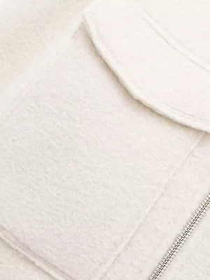 White cropped zip-up jacket with textured fabric and chest pockets.