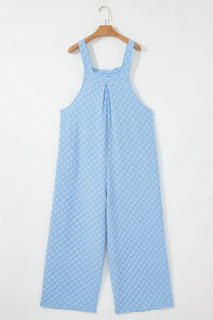 Light blue checkered textured palazzo jumpsuit with button straps and wide legs.