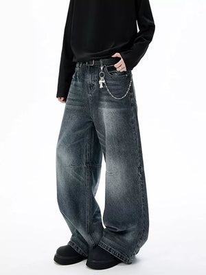 Belted wide-leg jeans in dark wash denim with unique paneled design and chain detail.
