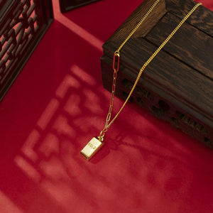 Gold-plated bar pendant necklace with curb links and a paperclip chain detail.