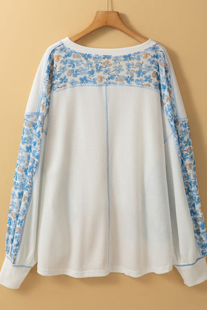 White waffle knit blouse with blue floral print sleeves and neckline detail