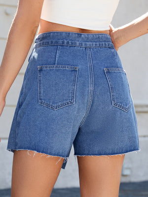 Medium wash denim skort with asymmetric wrap, raw hem, and back pockets.