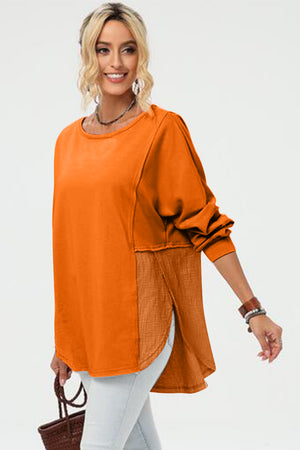 Tangerine split-panel sweatshirt with asymmetric hemline and crew neck.