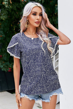 Dark blue dotted polyester blouse with flutter sleeves and pom-pom trim.