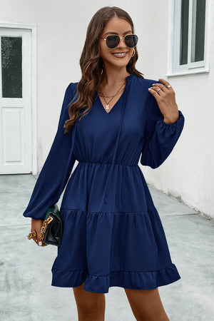 Navy tiered ruffle sleeve mini dress with tie neck and smocked waist.