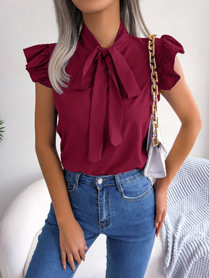 Burgundy ruffled sleeve pussybow blouse with a tie neck, styled with jeans.