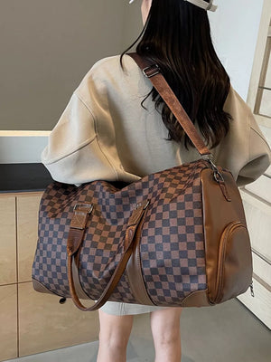 Chic checkered travel bag with brown leather accents and adjustable strap.