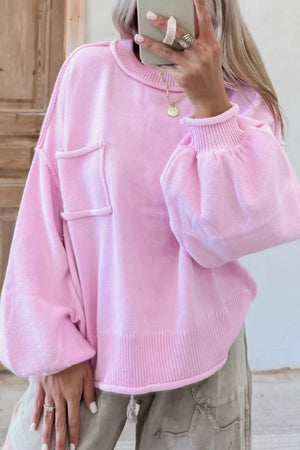 Pink knit sweater with puffed sleeves, contrast stitching, and a chest pocket.
