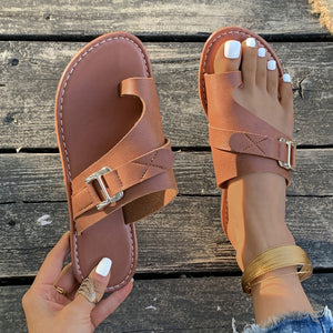 Brown toe loop flat sandals with buckle detail and crisscross straps.
