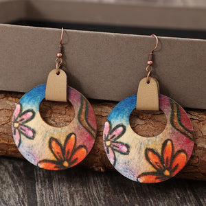 Painted floral wood hoop earrings with orange and pink blooms, featuring a tan leather accent.