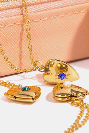 Gold heart lockets with gemstone and pearl details on a delicate chain.