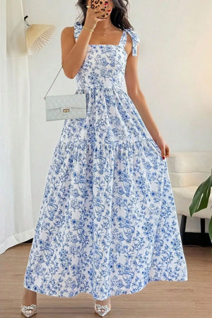Maxi dress with blue floral print, square neck, tie straps, and tiered skirt.