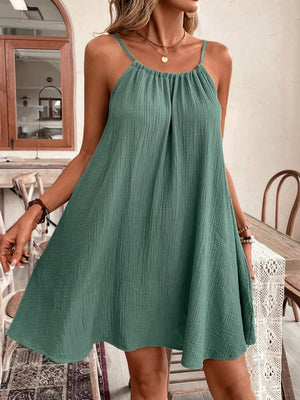 Turquoise spaghetti strap mini dress with gathered neckline and textured fabric.