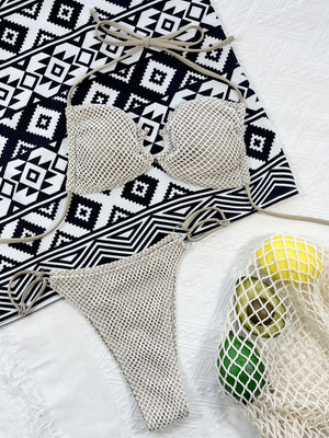 Ivory crochet halter bikini set with tie straps and matching bottoms on a patterned towel.