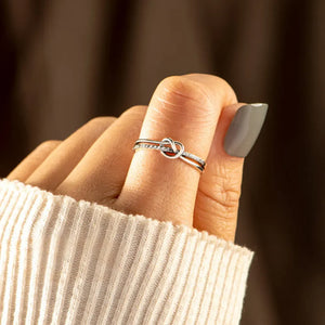 Silver knot ring with pavé detail on a finger, styled with a cream sweater.