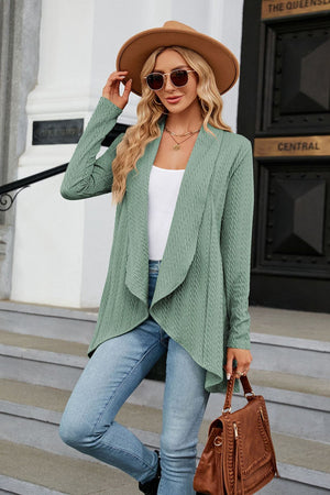 Sage green cable knit cardigan with drape front and open closure, styled with jeans.