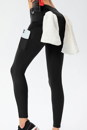 Black athletic leggings with phone pocket and utility pockets, towel draped on hip.
