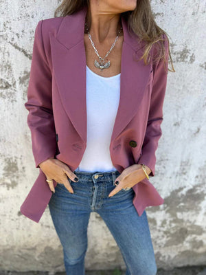 Dusty pink double-breasted blazer with sculpted lapels and button detail, styled with a white top and jeans.