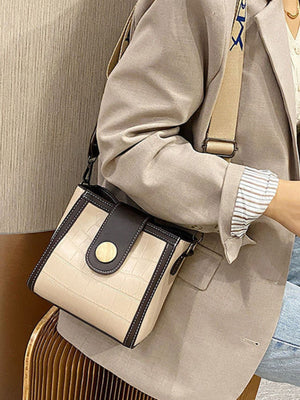 Khaki crocodile pattern mini crossbody bag with dark brown trim and gold button closure.