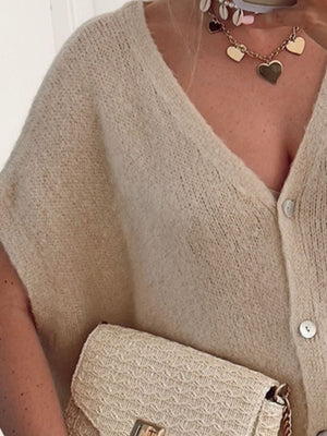 Khaki cap sleeve mohair blend cardigan with V-neck and buttons, styled with a straw clutch.