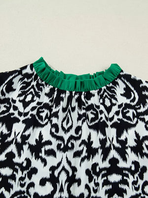 Damask print maternity blouse with ruffled green neckline and half sleeves.