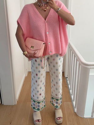 Pink mohair cap sleeve cardigan with pearl buttons, styled with patterned pants and a pink woven crossbody bag.