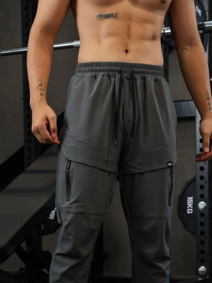 Gray technical joggers with zip pockets and drawstring waist.