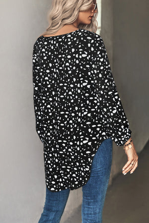 Black dalmatian print blouse with balloon sleeves and a curved hem.