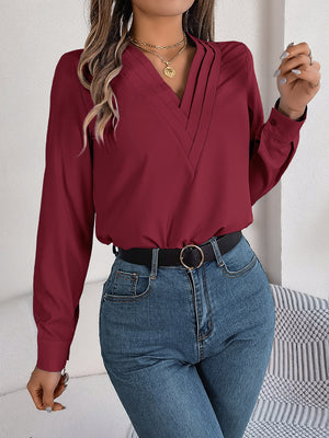 Burgundy V-neck blouse with pleated detail and long sleeves.