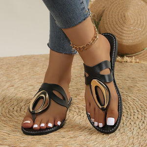 Black open-toe sandals with golden oval accent and contrast stitching.
