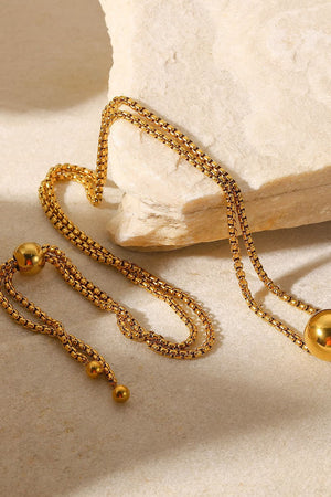 Gold orb pendant necklace with adjustable chain and bead details.
