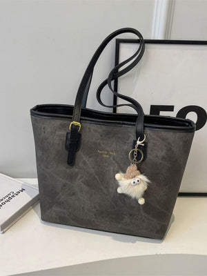 Distressed dark gray pu leather tote bag with buckle accents and a fuzzy charm.