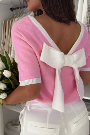 Pink knit top with white contrast trim and a large bow detail on the back.