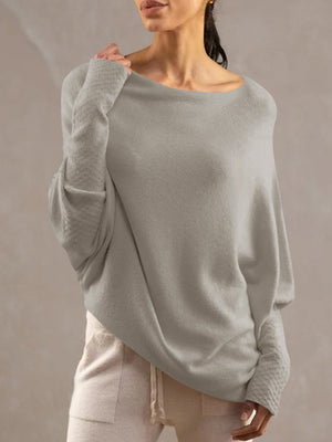 Light gray off-shoulder knit sweater with textured cuffs and draped fit.