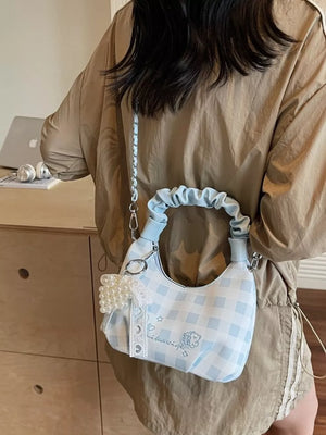 Light blue checkered crossbody bag with ruched handle and pearl charm.