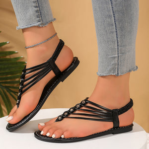 Black studded slim strap toe post sandals with elastic heel strap and white stitching.