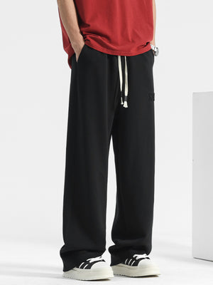 Men's black casual drawstring sweatpants with embroidered logo detail.