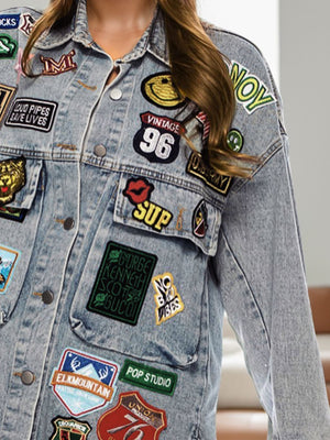 Embroidered denim trucker jacket in medium wash with assorted patches.