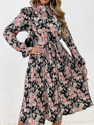 Black floral midi dress with pink roses, long sleeves, tie waist, and pleated skirt.