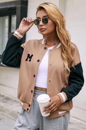 Camel bomber jacket with black sleeves, white striped cuffs, and an M patch.
