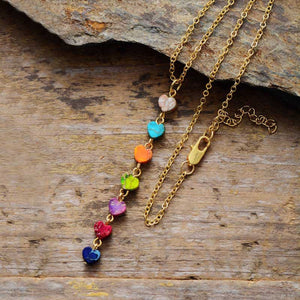 Gold chain necklace with multicolor heart charms cascading down.