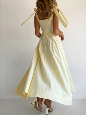 Yellow maxi dress with bow tie shoulder straps and a square neckline.