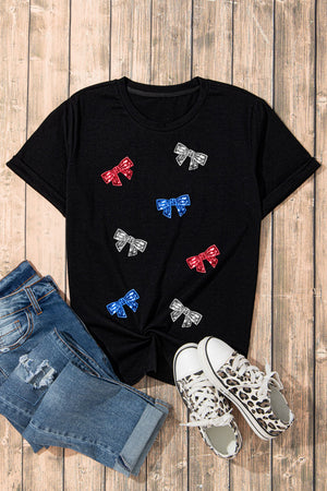 Black crewneck tee with scattered red, blue, and silver bow embellishments.